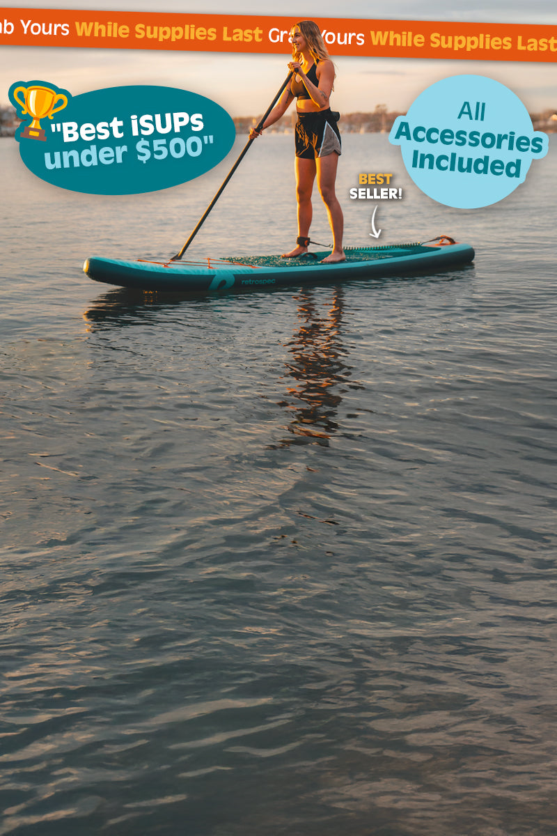 Woman paddling a retrospec inflatable Paddle Board across calm water at sunset.