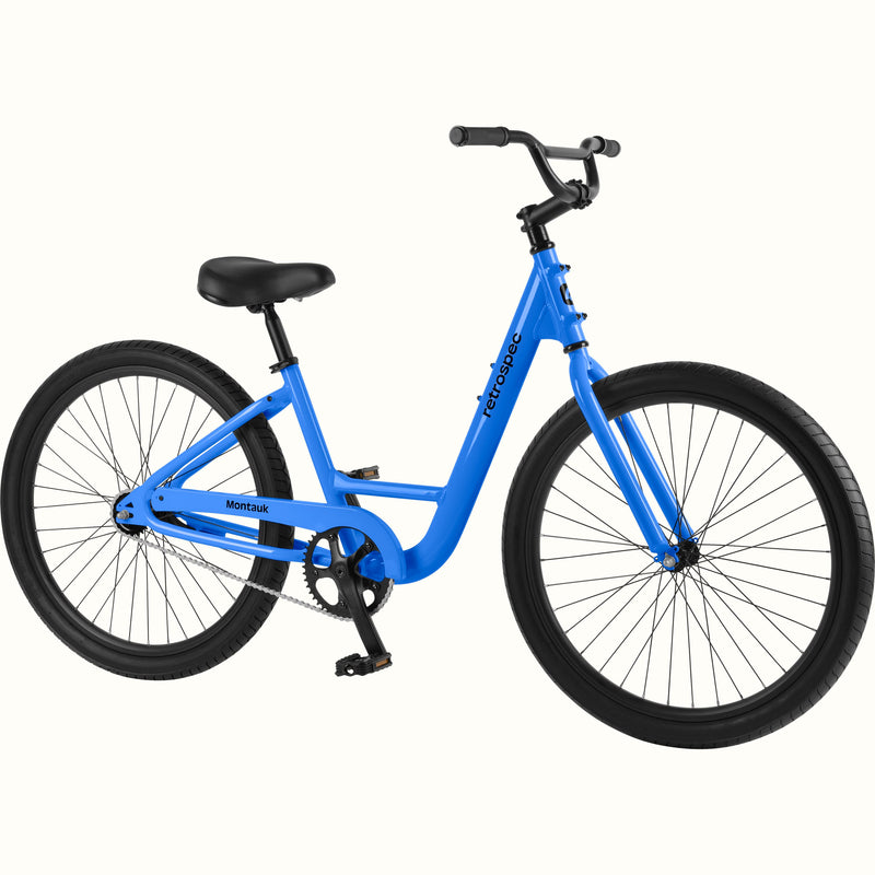 retrospec Montauk cruiser bike in cobalt blue with a low step-through frame, black tires, saddle, and upright handlebars, shown on a clean white background.