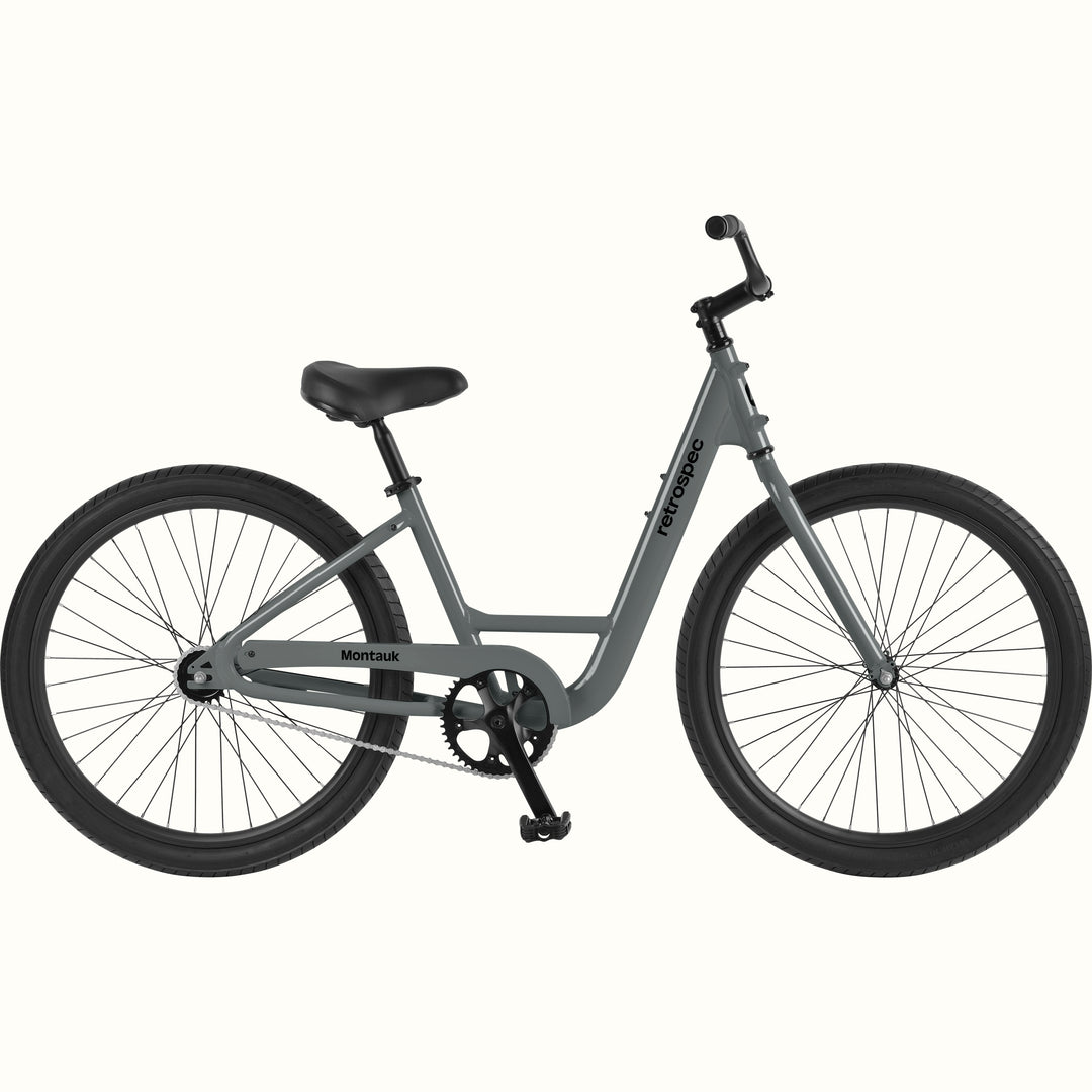 retrospec Montauk cruiser bike in graphite with a low step-through frame, black tires, saddle, and upright handlebars, shown on a clean white background.