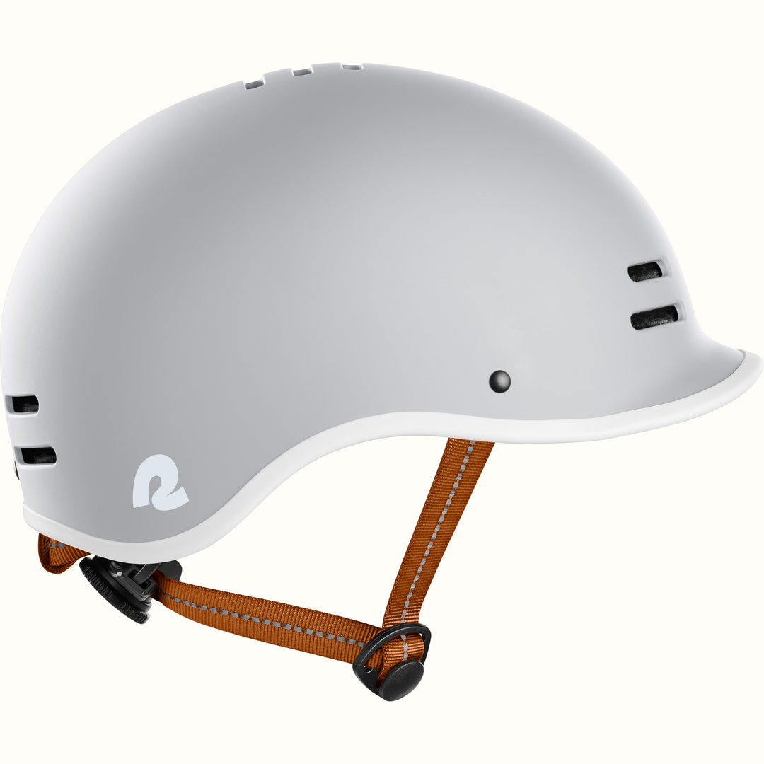 Gray bike helmet with adjustable brown straps, featuring ventilation holes and a stylish logo on the side.
