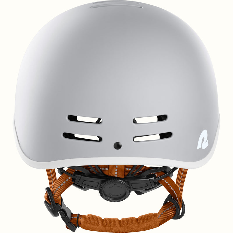 Gray bike helmet with adjustable brown straps, featuring ventilation holes and a stylish logo on the side.