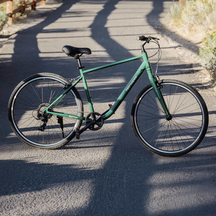Sycamore green Barron Comfort Hybrid 7 Speed Bike on a paved path with a blurred background.