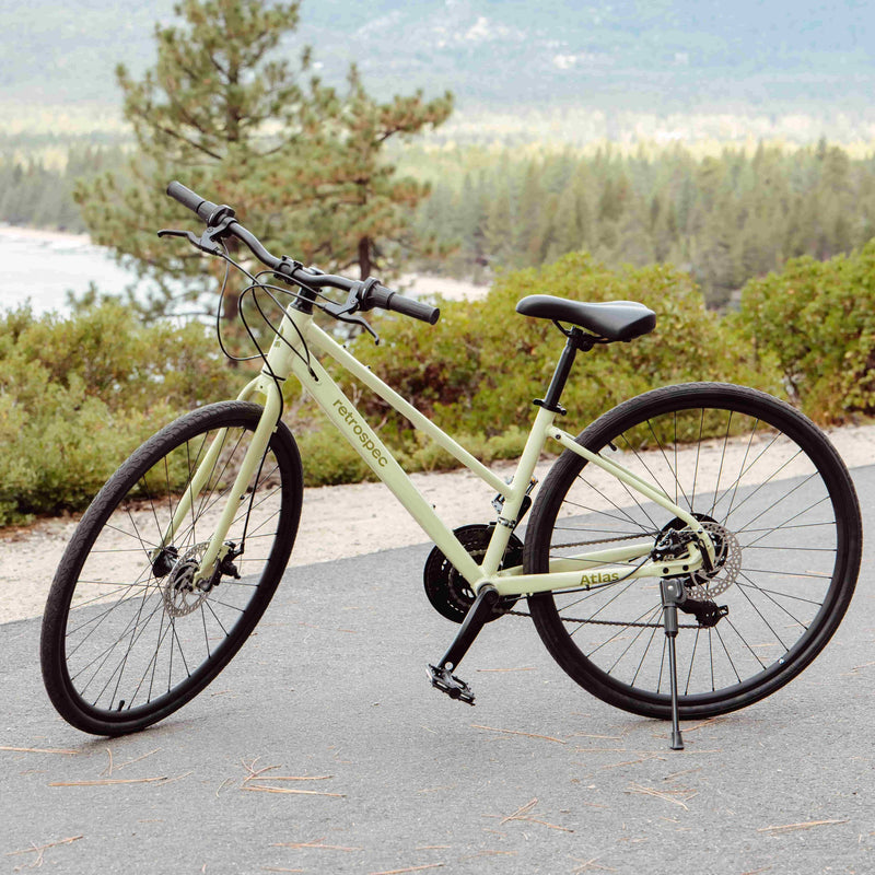 Light green bicycle on a paved path with a scenic background of trees and water.