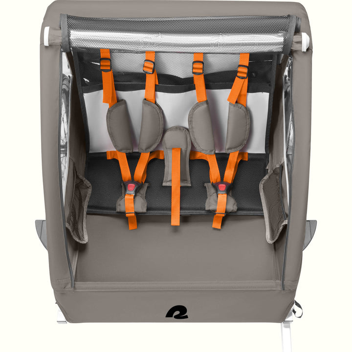 A Rover Plus Child Double bike trailer with a mesh front, featuring orange harness straps and a sturdy frame, designed for safety and comfort.