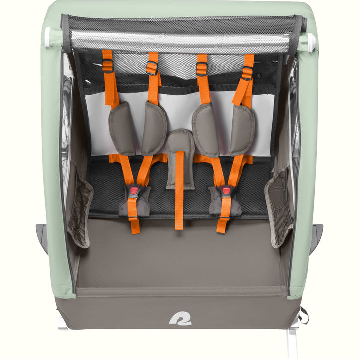 A Rover Plus Child Double bike trailer with a mesh front, featuring orange harness straps and a sturdy frame, designed for safety and comfort.