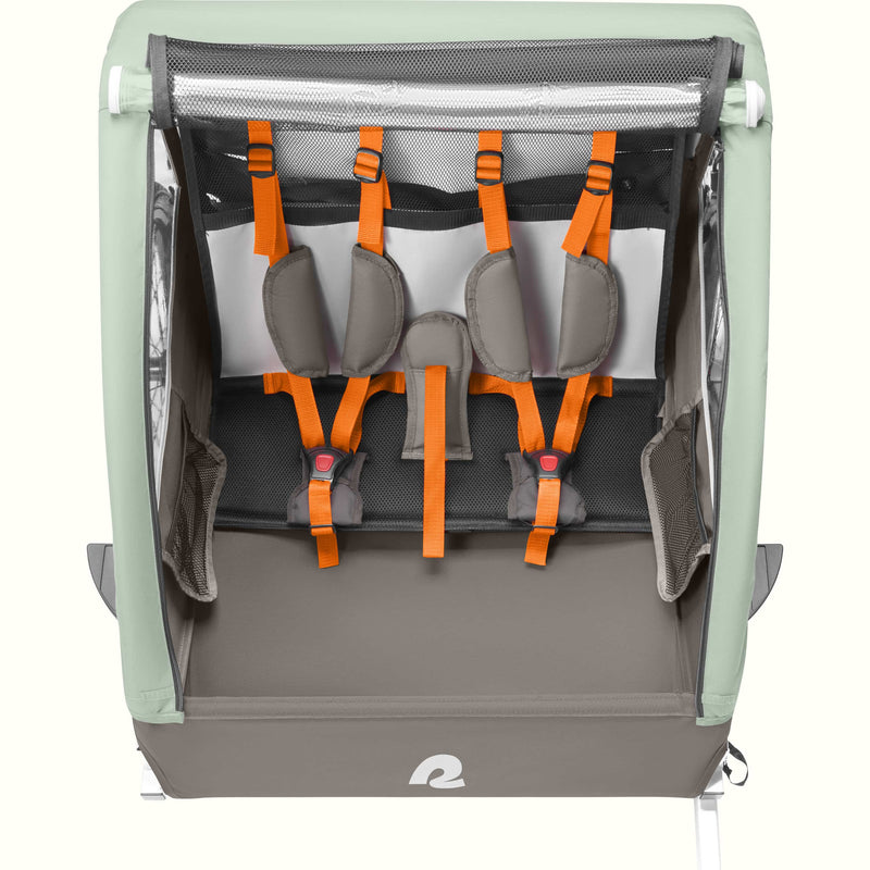 A Rover Plus Child Double bike trailer with a mesh front, featuring orange harness straps and a sturdy frame, designed for safety and comfort.