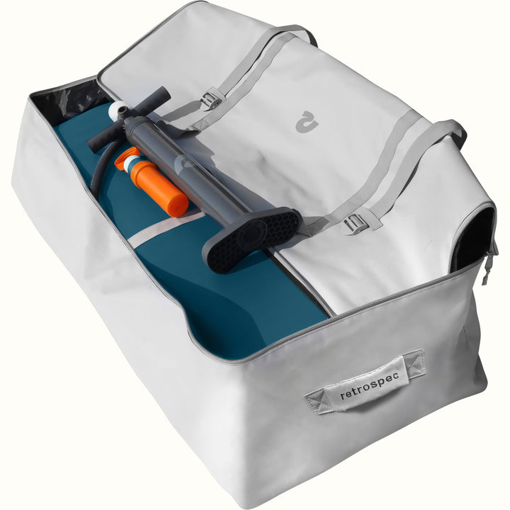 An open gray bag with a deflated Siesta XL Inflatable Platform, a floor pump, and repair kit inside.