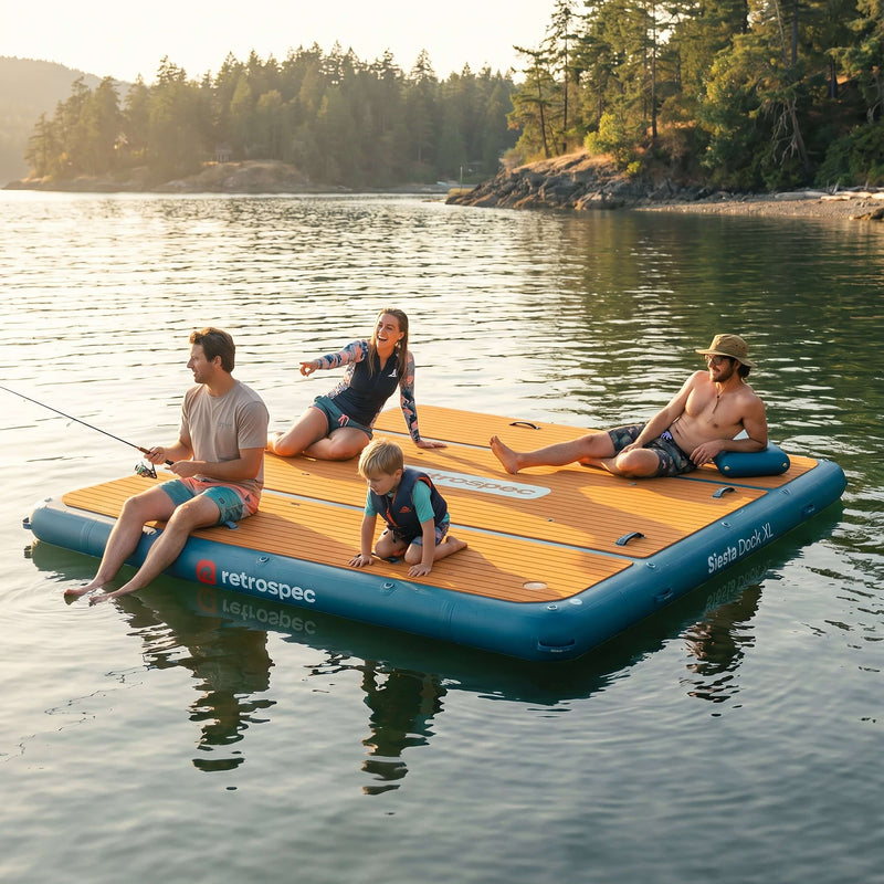 Family fishing and relaxing on a retrospec Siesta Dock XL inflatable floating dock on a calm lake at golden hour.

