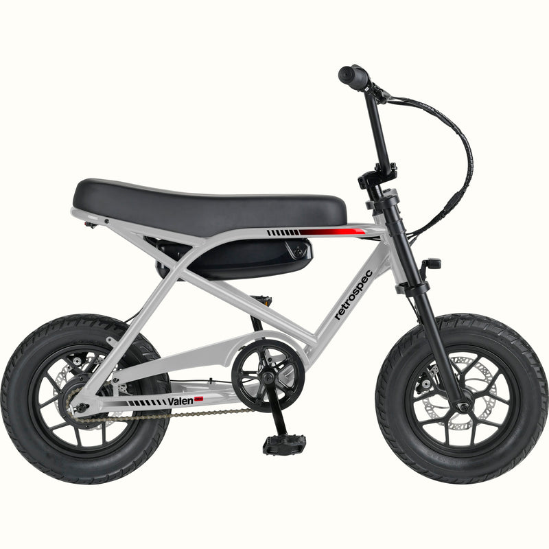 A compact electric mini bike with a silver frame, black seat, black tires, and black handlebars, shown from a side profile on a solid white background. The brand names 'retrospec' and 'Valen Rev' are visible on the frame.