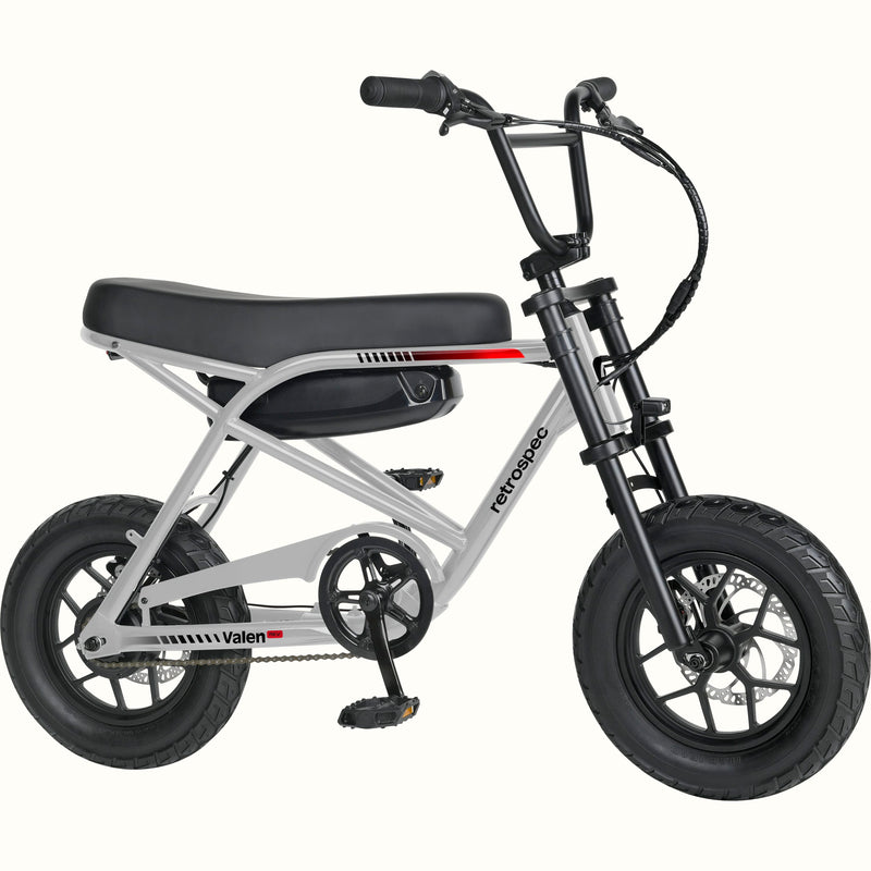 A mini electric bicycle with a silver frame, black seat and tires, and a black battery pack mounted on the rear frame, shown against a plain white background.