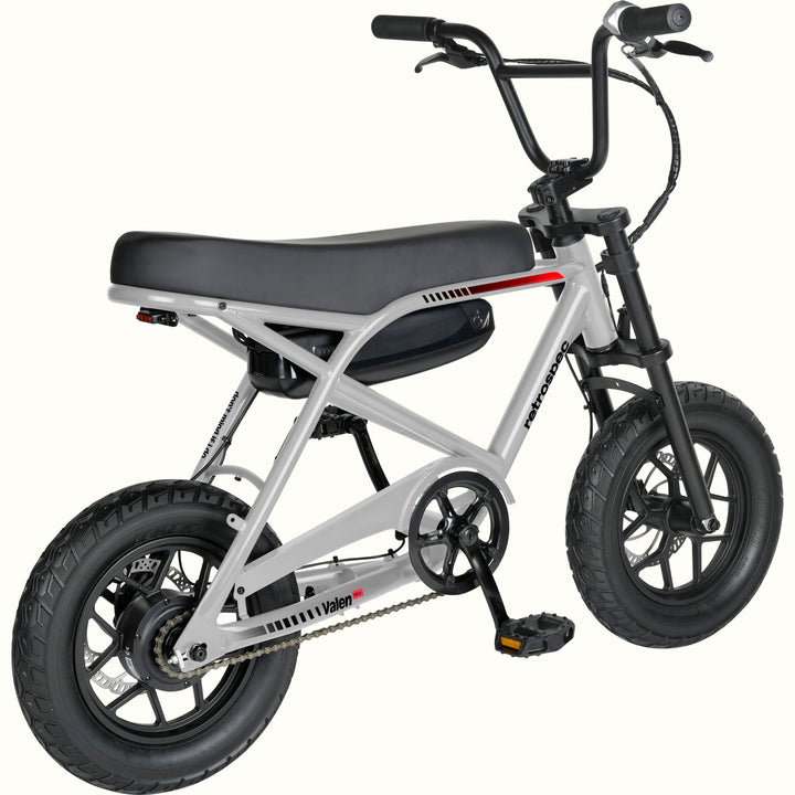 A small electric bike with a silver frame, black seat, black tires, and a black battery pack mounted on the frame, shown against a plain white background.