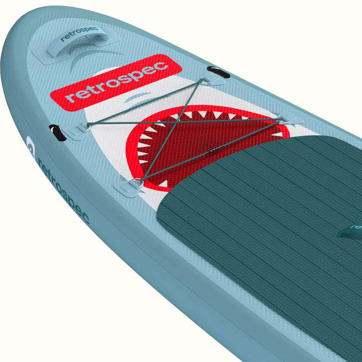 Close-up of the Weekender Nano Kids Inflatable Paddle Board's nose with retrospec logo and shark design with four point bungee for storage.