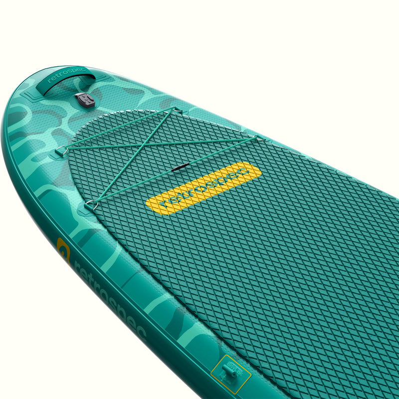The nose of a teal Weekender Yogi Stand Up Inflatable Paddle Board with a yellow logo and textured deck pad on a white background.