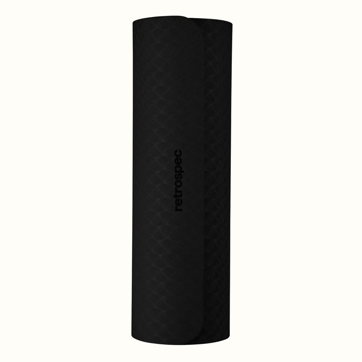 Rolled up black Zuma Yoga Mat with textured surface on a white background.