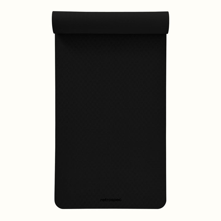 Partially rolled out black Zuma Yoga Mat with textured surface on a white background.
