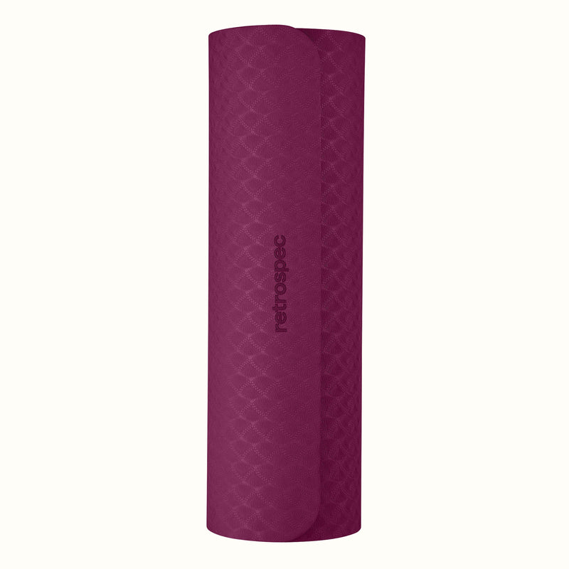 Rolled up Boysenberry Zuma Yoga Mat with textured surface on a white background.
