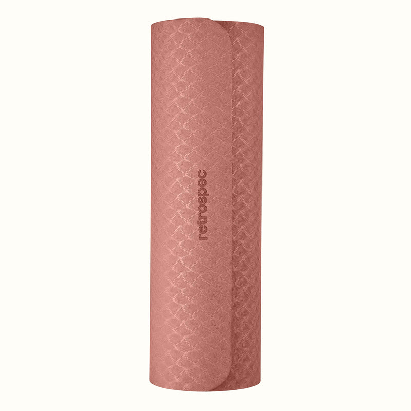 Rolled up Rose Zuma Yoga Mat with textured surface on a white background.