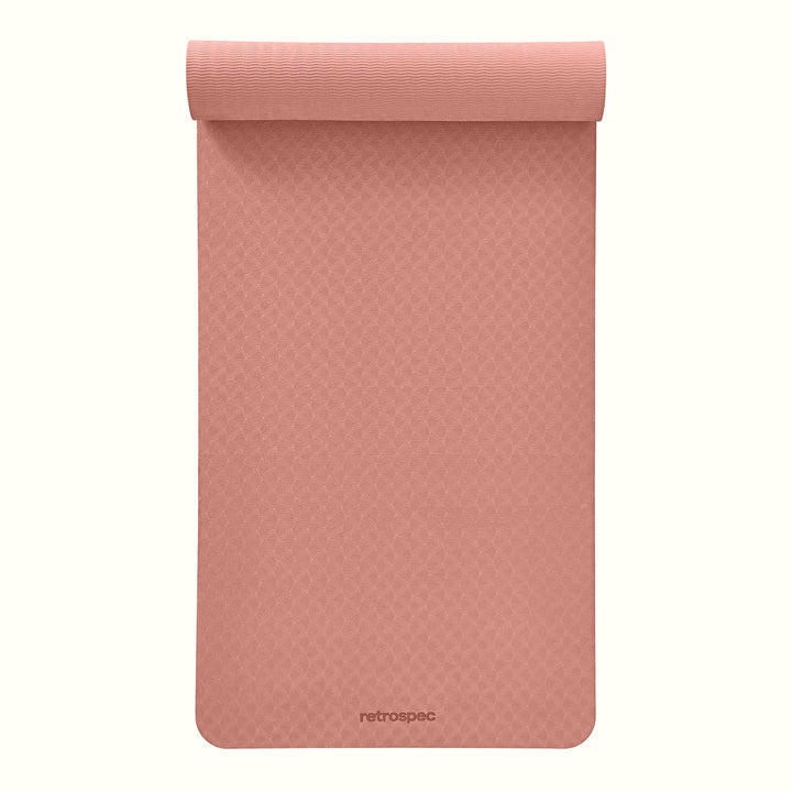 Partially rolled out Rose Zuma Yoga Mat with textured surface on a white background.