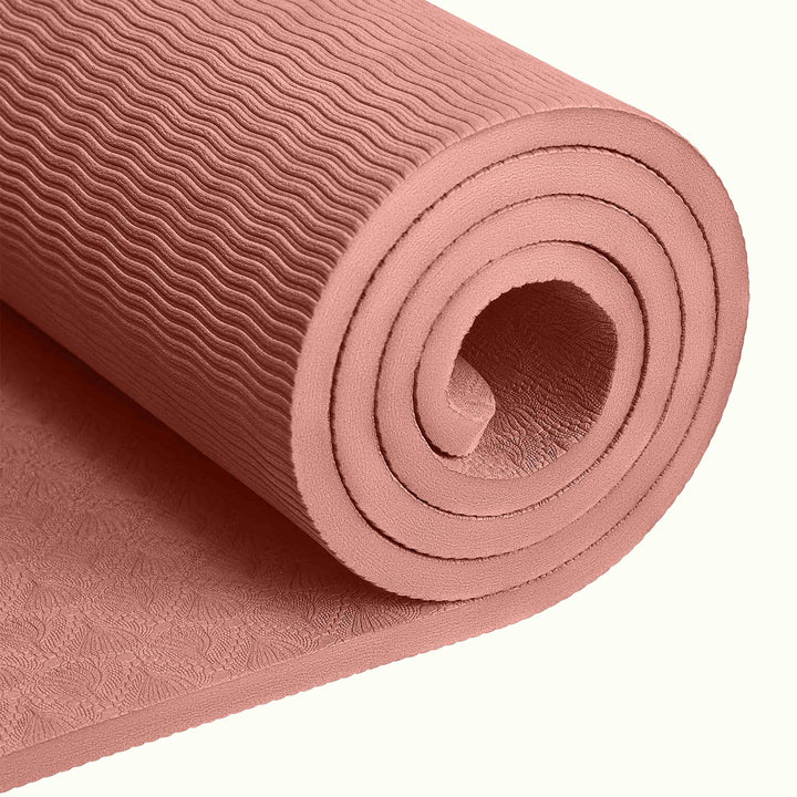 Close-up of a tightly rolled Rose textured Zuma Yoga Mat with wavy patterned surface on a white background.
