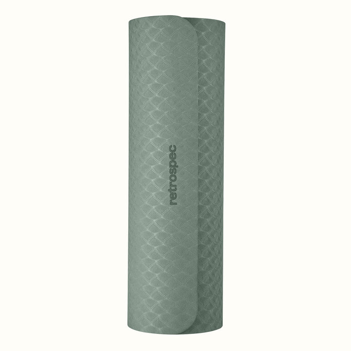 Rolled up Sage Zuma Yoga Mat with textured surface on a white background.