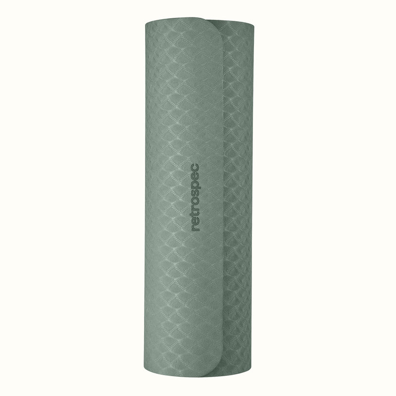 Rolled up Sage Zuma Yoga Mat with textured surface on a white background.