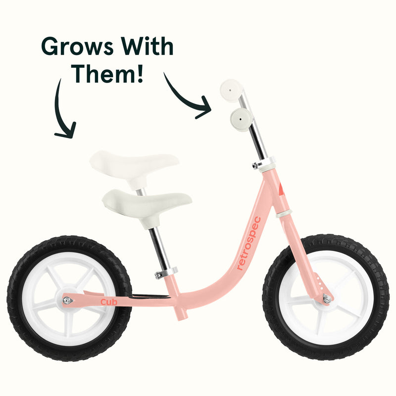 Pink Cub Balance bike with text 'Grows With Them!' on a white background.